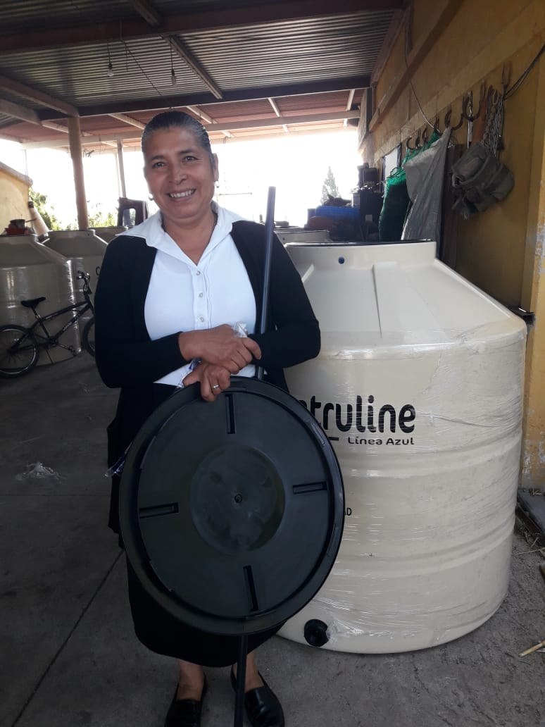 Beneficiaria junto a un tinaco entregado en Santa Rosa Jáuregui, Querétaro, 2022