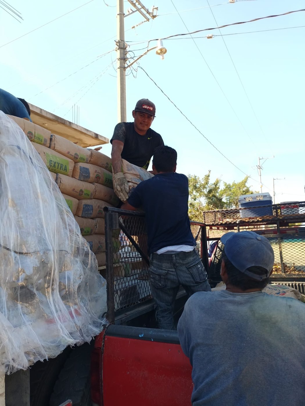Descarga de bolsas de cemento de un camión a una camioneta en Santa María Colotepec, Oaxaca, 2023