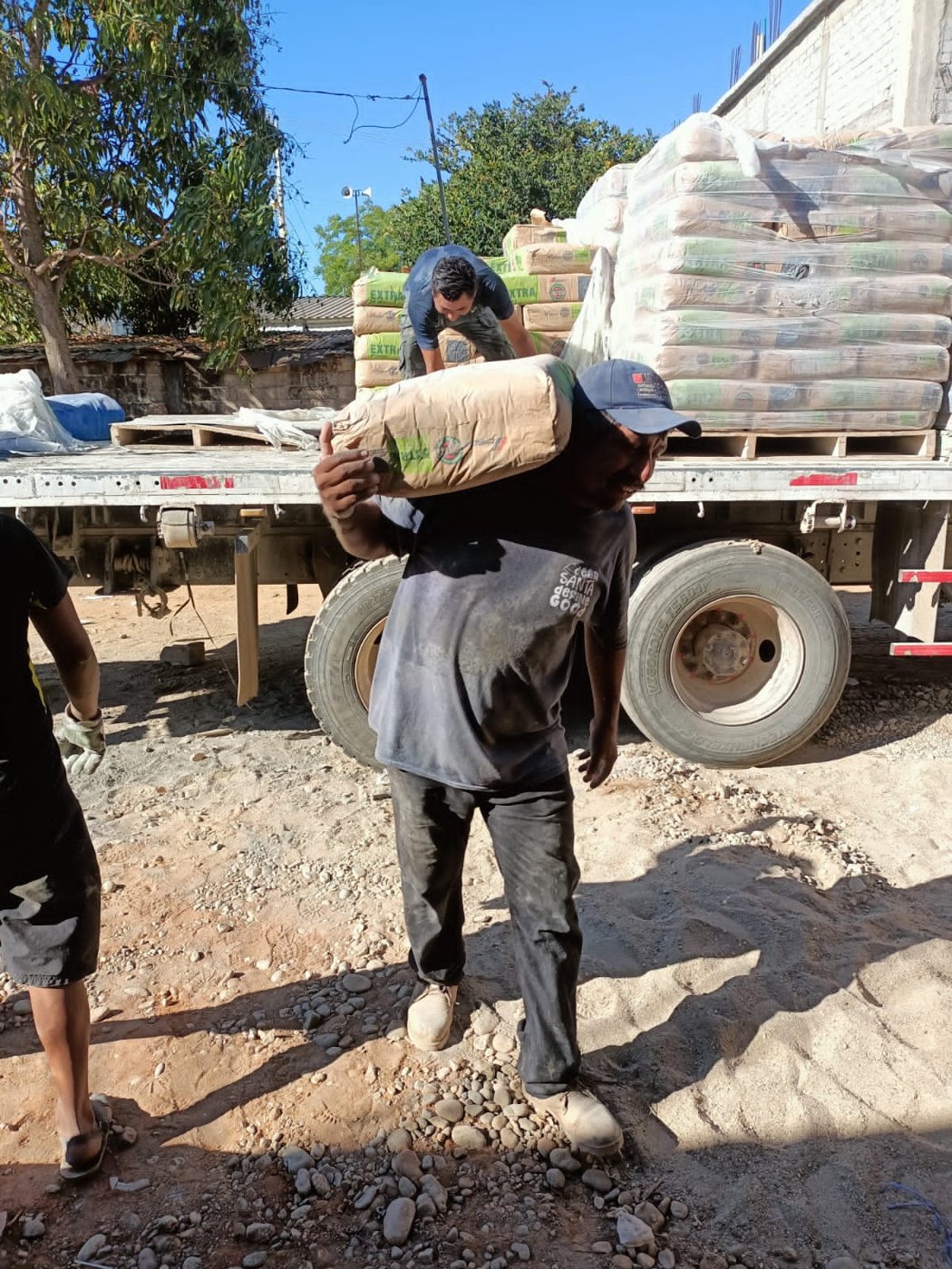 Trabajador cargando una bolsa de cemento durante la entrega en Santa María Colotepec, Oaxaca, 2023